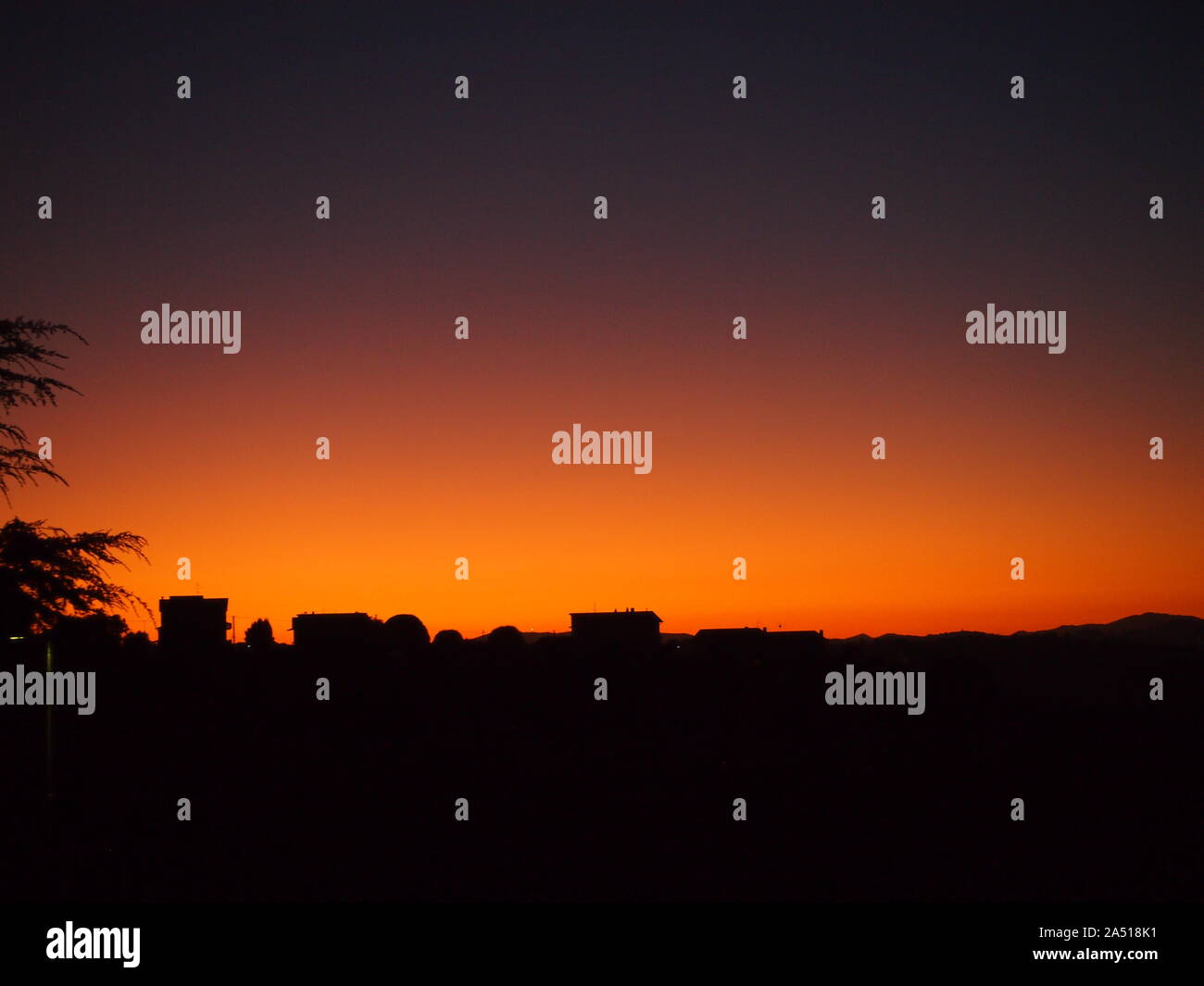 La silhouette des maisons par rose et orange sky à la première lumière de l'Ombrie, Italie Banque D'Images