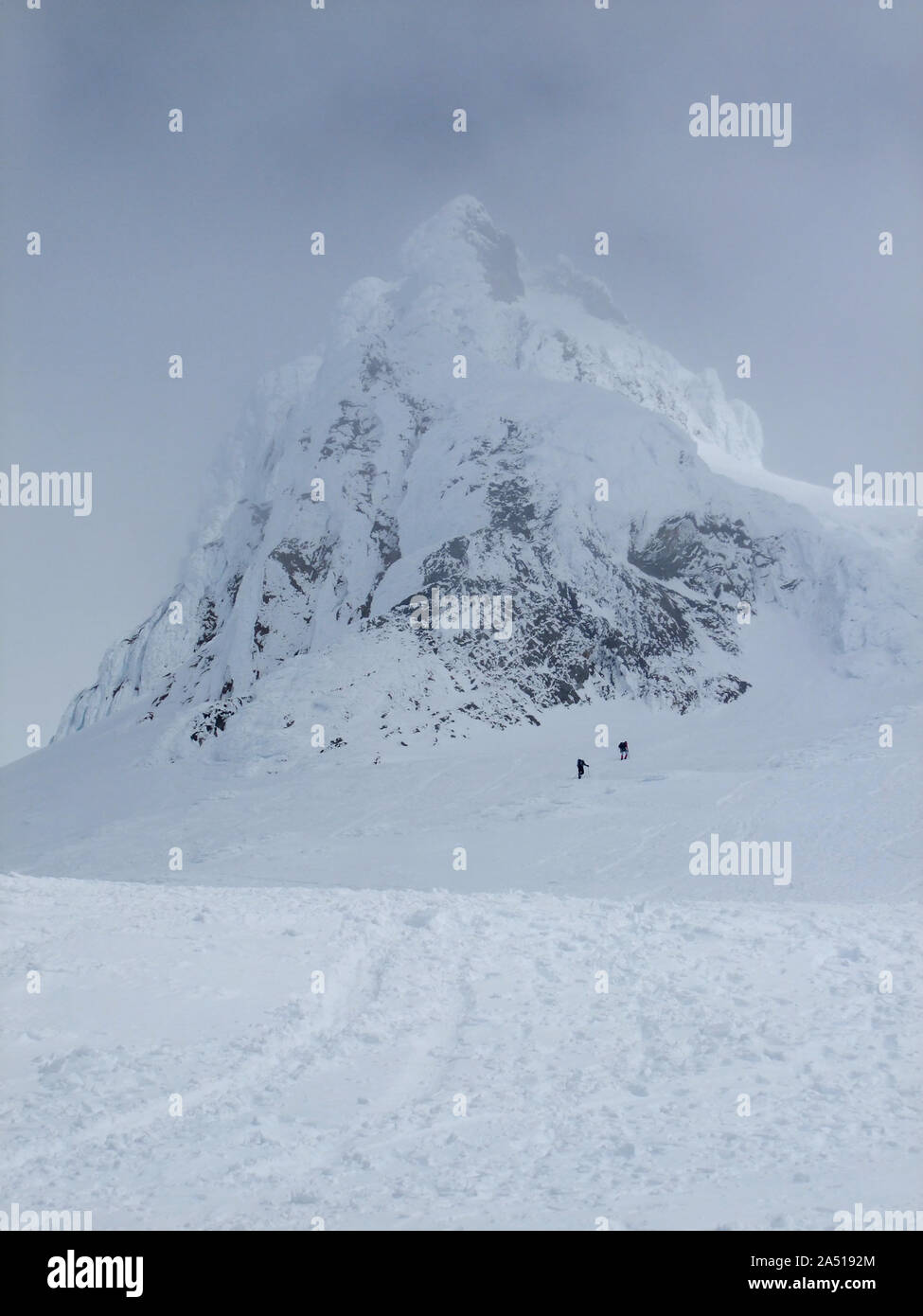 Deux alpinistes font leur chemin jusqu'Carter Rock, un vieux lave dome, sur Mt. Comme les nuages de la hotte à proximité. Banque D'Images