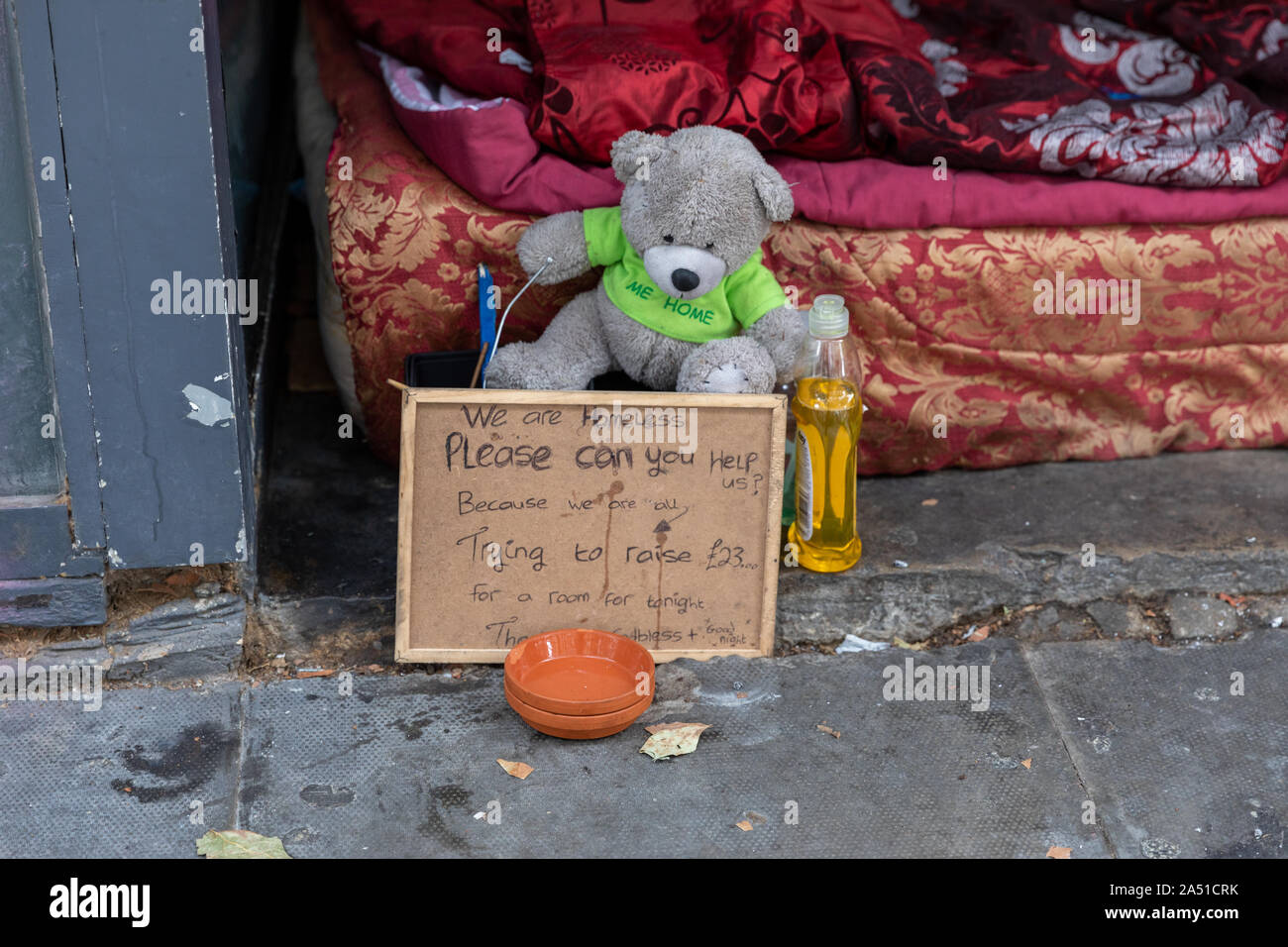 Une personne sans-abri et les possessions de literie dans l'embrasure d'une boutique sur une rue de la ville, et une note écrite, demander de l'aide à payer pour le gîte Banque D'Images