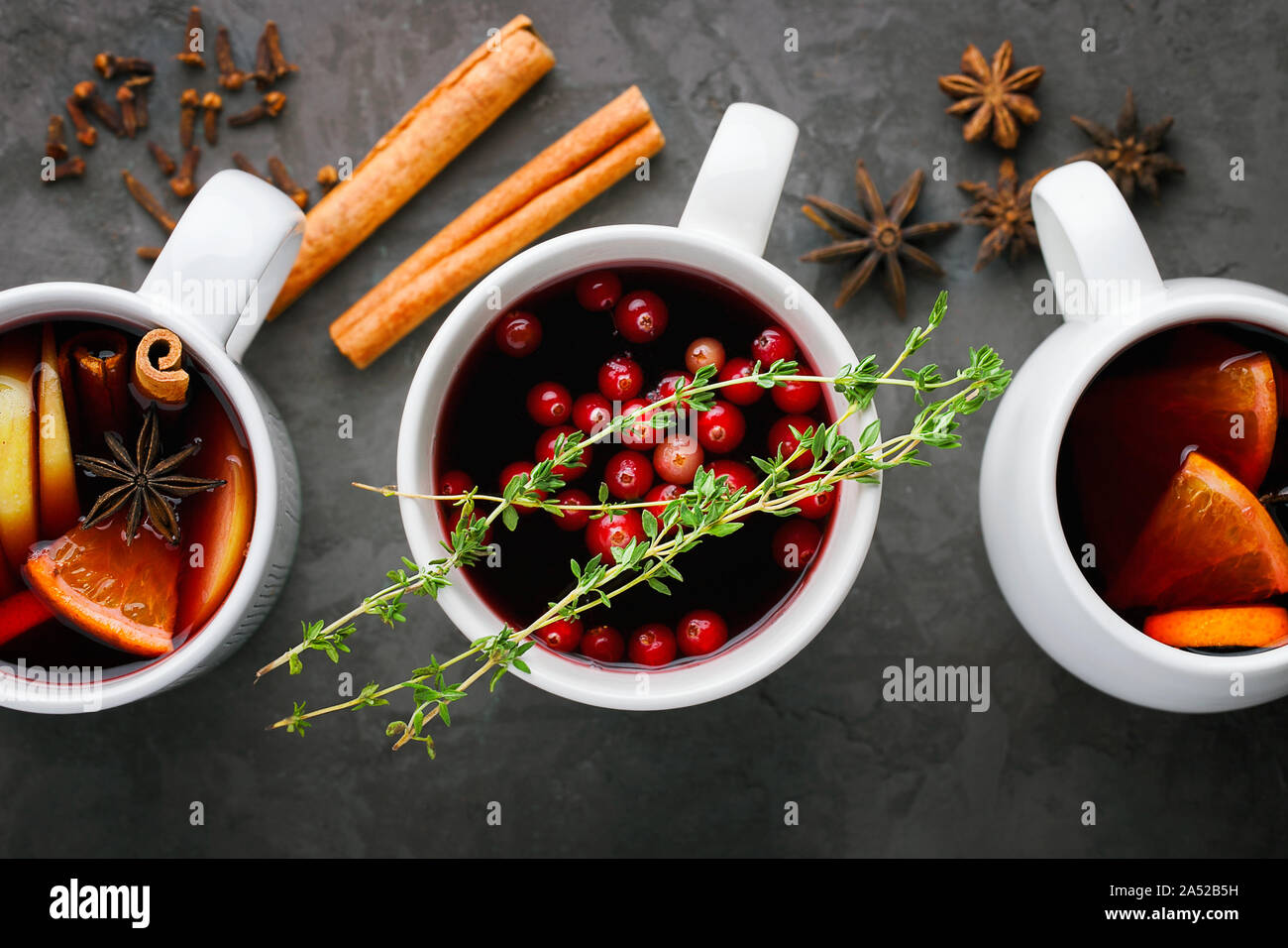 Vin chaud de Noël verre dans une tasse avec les agrumes orange,apple,des bâtons de cannelle et les étoiles d'anis sur fond de béton gris foncé top view Banque D'Images