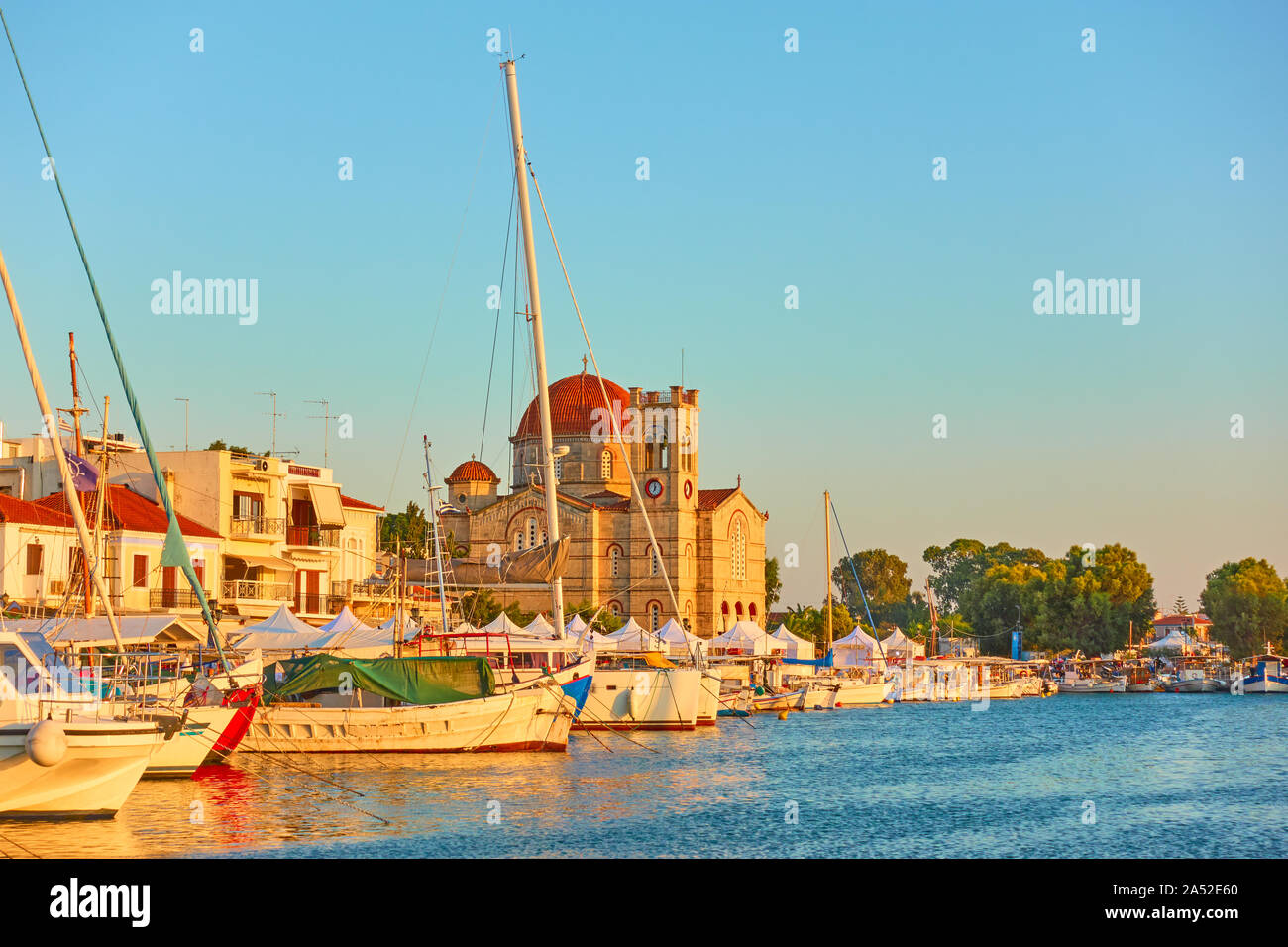 Yachts et waterfront avec Ekklisia Isodia Theotokou église au coucher du soleil dans la ville d'Egine, îles saroniques, Grèce Banque D'Images