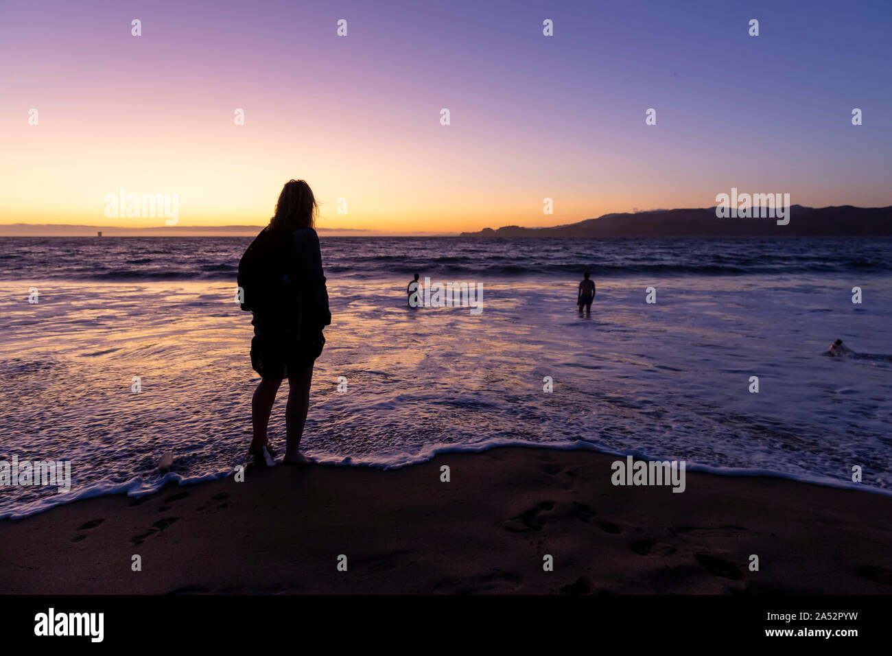 Silhouette d'une femme sur la pagaie, San Francisco Baker Beach au coucher du soleil Banque D'Images