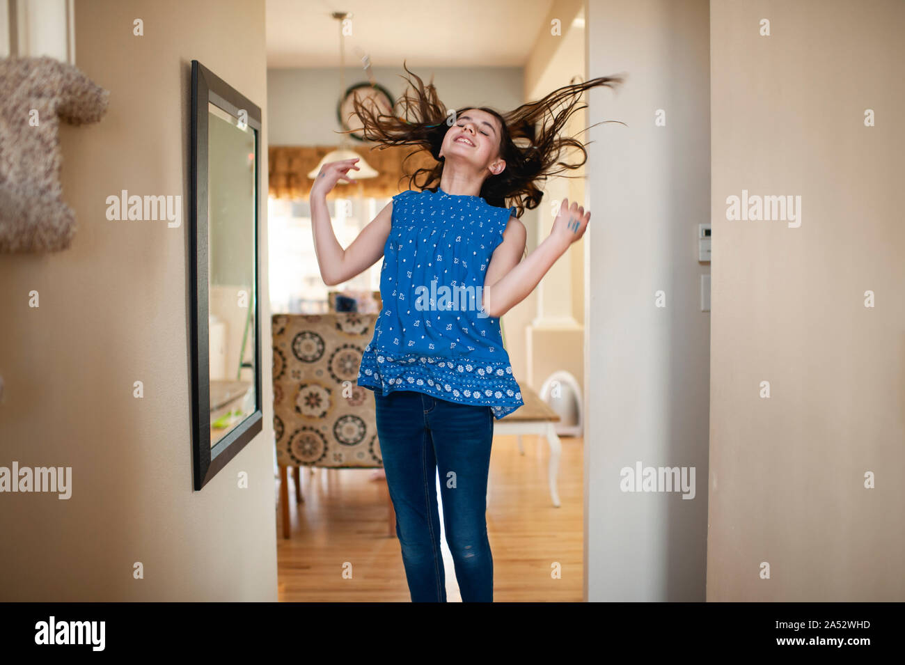 Teen girl jumping et renversant ses cheveux en face du miroir à la maison Banque D'Images