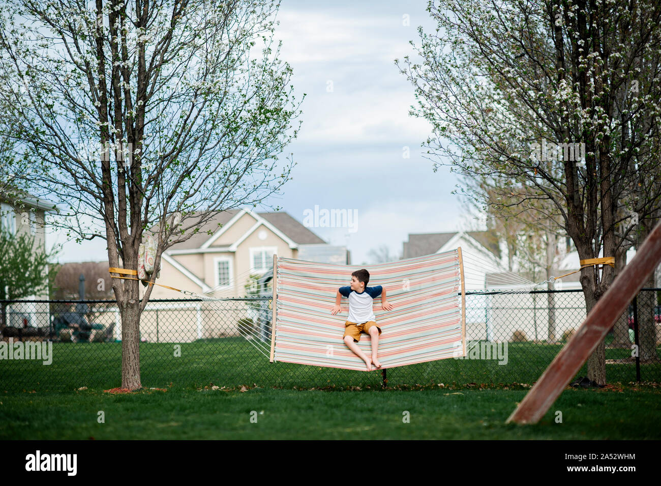 Garçon 7-8 ans se balançant dans un hamac dans le jardin au printemps Banque D'Images