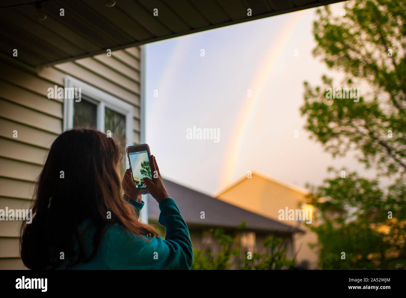 Teen girl taking photo de rainbow avec son téléphone intelligent à l'extérieur Banque D'Images