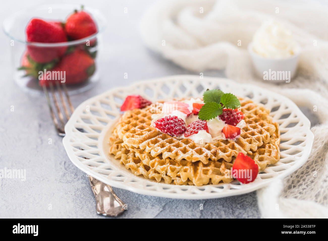 Les gaufres suédoises avec fraises et crème. Il y a un bol en verre avec des fraises entières et d'un petit bol en céramique de crème fouettée à l'arrière-plan Banque D'Images
