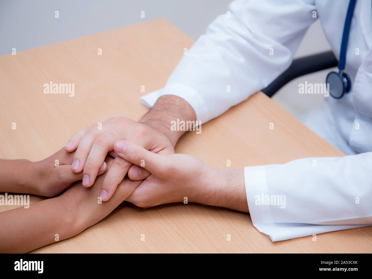 Friendly médecin homme main tenant la main du patient assis au bureau pour l'encouragement - empathie - encourager et soutenir alors que l'examen médical. Banque D'Images
