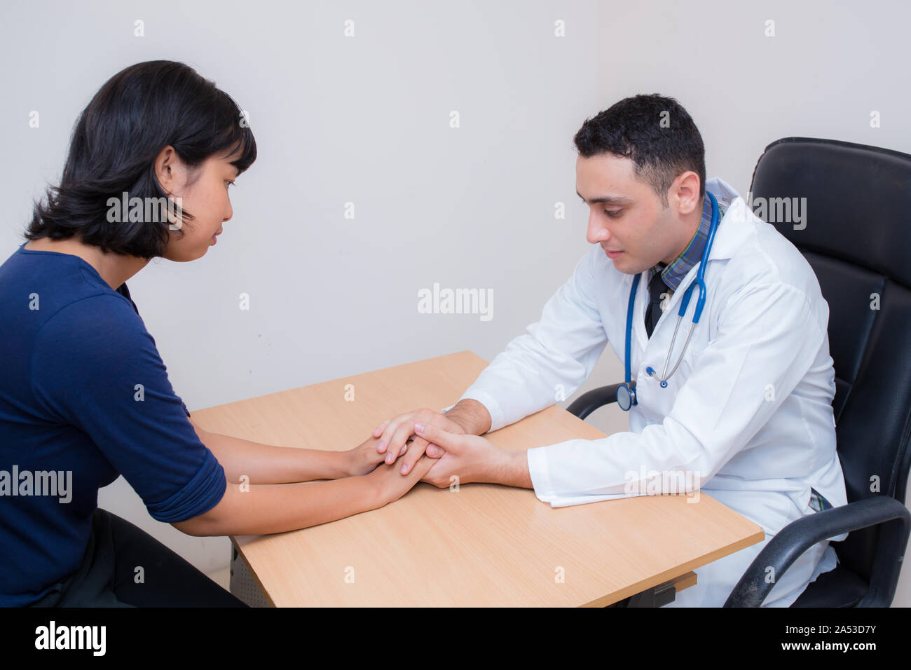 Friendly médecin homme main tenant la main du patient assis au bureau pour l'encouragement - empathie - encourager et soutenir alors que l'examen médical. Banque D'Images
