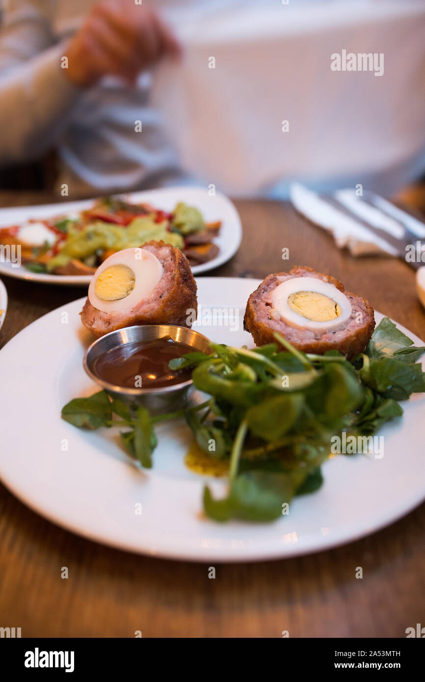Repas au restaurant Taverne de gazon, Oxford (Royaume-Uni). Boulettes d'oeufs délicieux oeufs scotch (Cumberland) servi avec salade verte fraîche. Banque D'Images