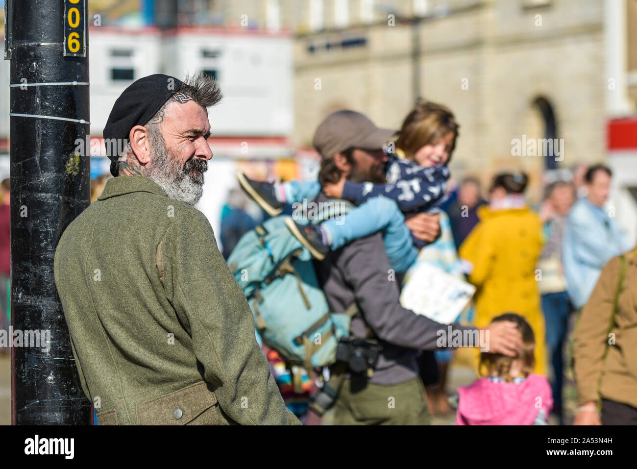 Un homme avec une barbe et des tatouages regarder les gens participant à la rébellion Extinction grève climatique à Truro, Ville Ville de Cornwall. Banque D'Images