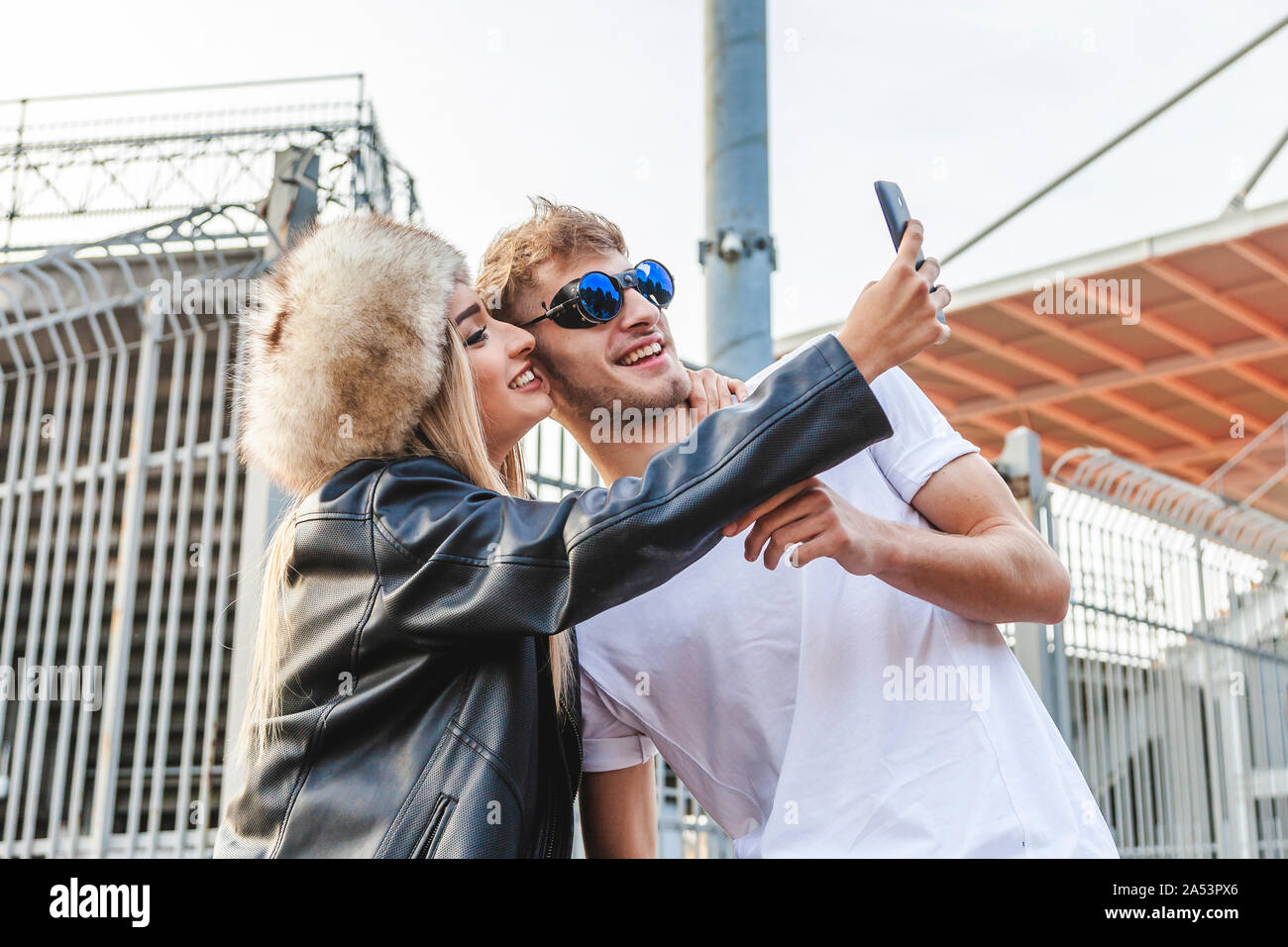 Couple de jeunes amateurs de beaux selfies prendre sur la grande place d'un stade Banque D'Images