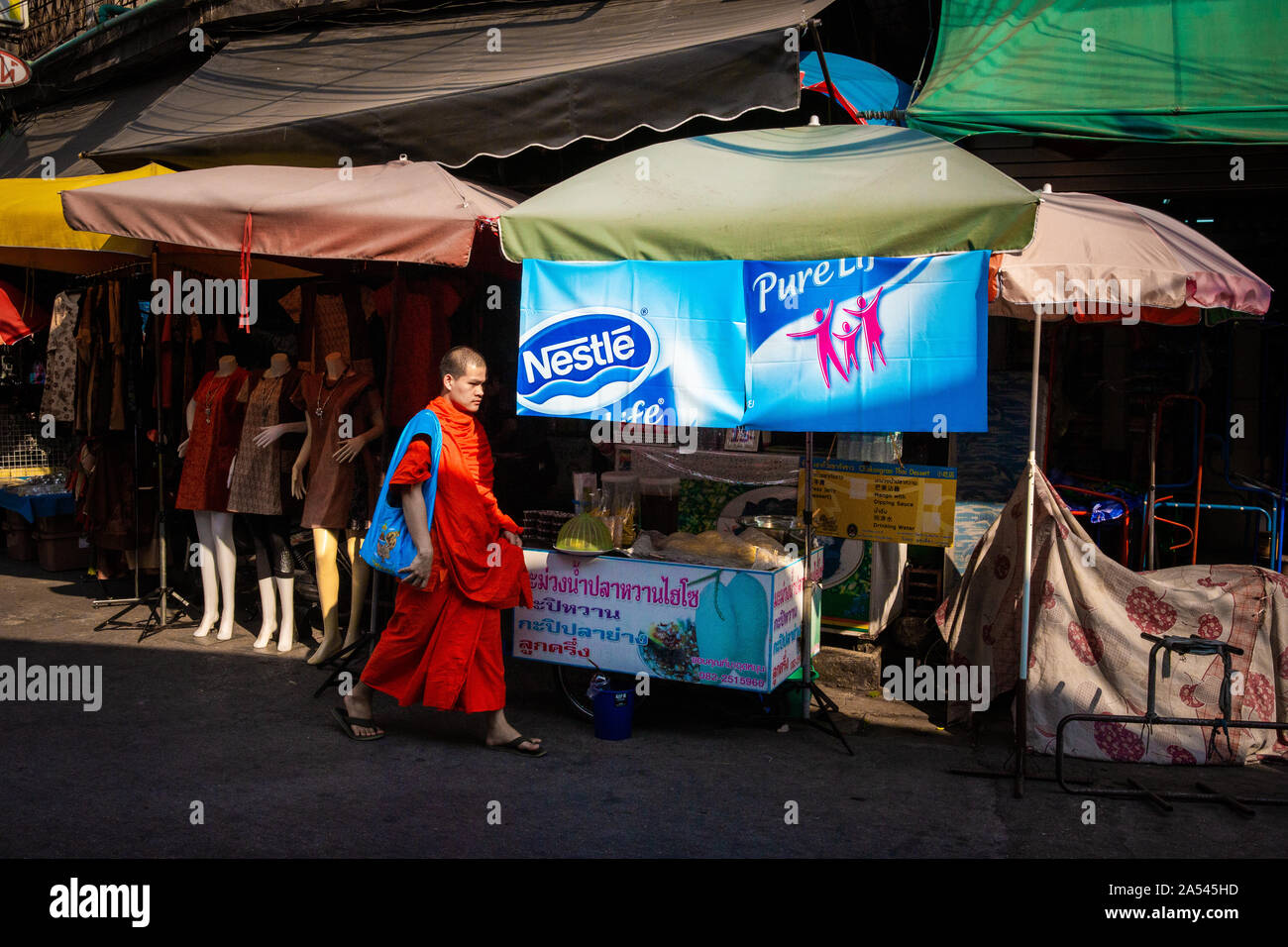 Le moine bouddhiste en robe orange marche dans la zone commerçante de Chiang Mai, Thaïlande. Banque D'Images