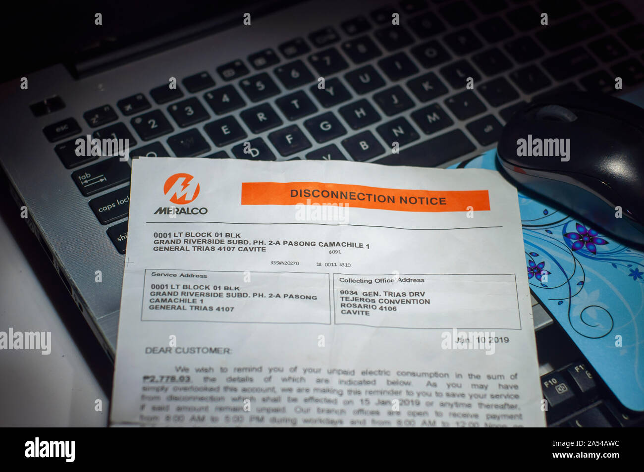 Sombre dramatique tourné de MERALCO local de l'avis de débranchement Filipino Electric company placé sur le haut d'un ordinateur au clavier sur un lieu de travail. Banque D'Images