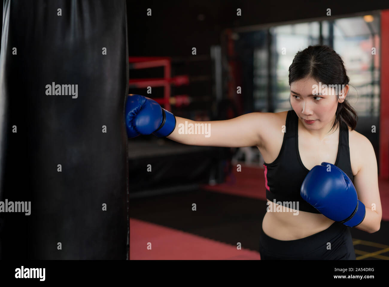 Portrait de jeune femme asiatique confiant boxer bleu avec des gants de boxe, un sac de frappe dans professioal de sport. S'adapter aux modes de vie sportive modèle asiatique Banque D'Images