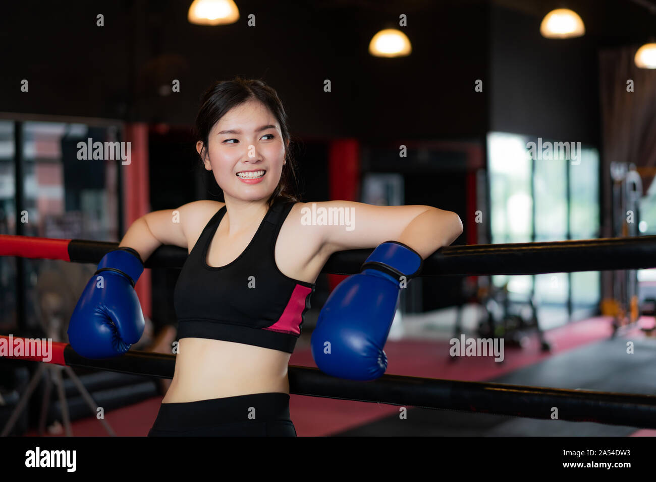 Boxer fille sports asiatiques fatigués se pencha sur noir rouge des cordes sur ring de boxe, et se reposer après un entraînement intensif en noir de sport. loft Mettre en place pour une sportive Banque D'Images
