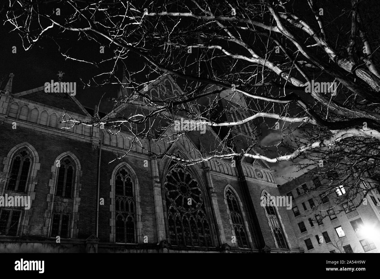 La nuit Creepy shot d'une vieille église avec des branches d'arbre en premier plan, en noir et blanc Banque D'Images