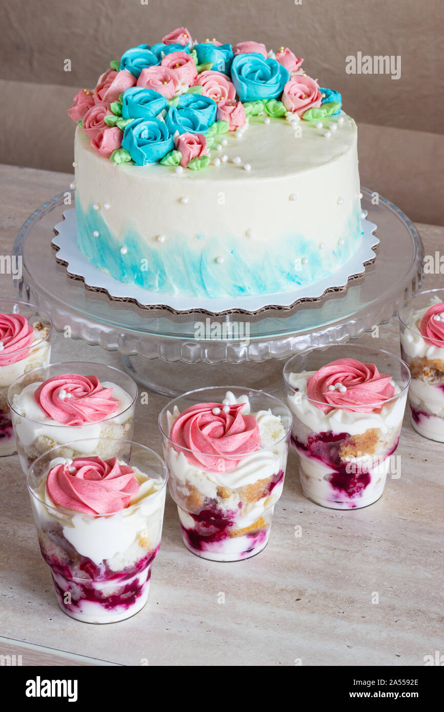 Gâteau de fête avec des roses crème et dessert dans un verre sur un fond clair. Banque D'Images