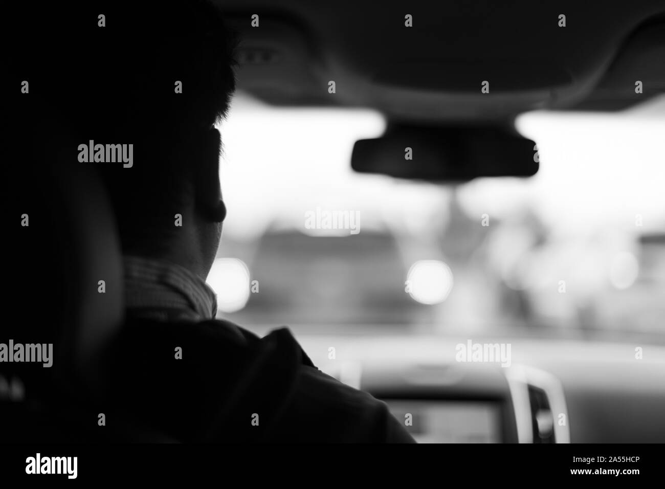 Homme conduisant en voiture à jour de pluie, flou, noir et blanc Banque D'Images