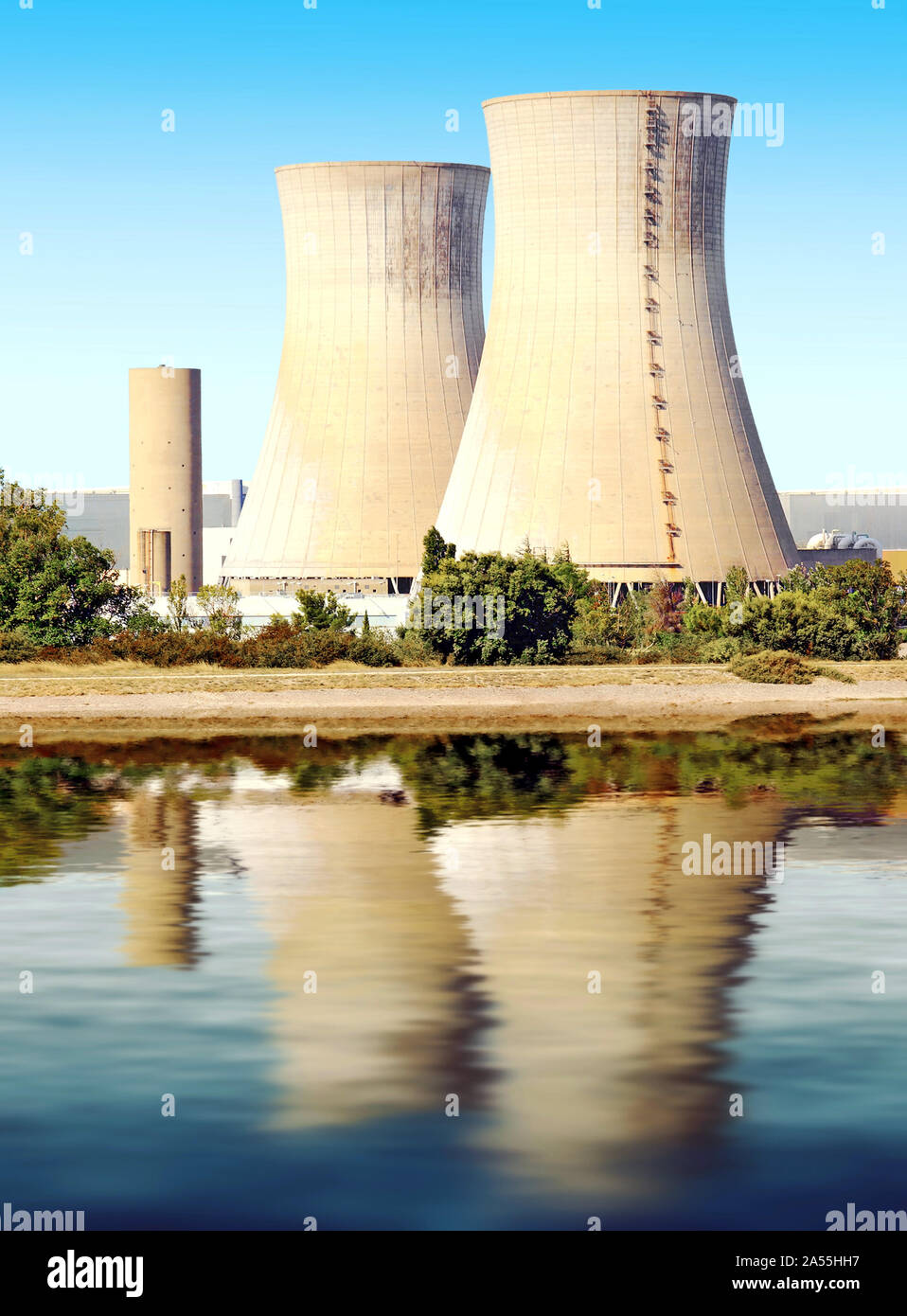 Les cheminées des centrales nucléaires se reflétant dans l'eau. Banque D'Images