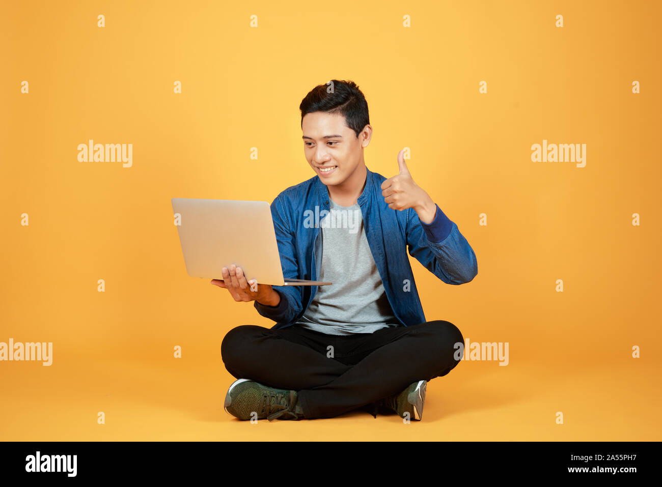 Heureux heureux Asian man holding laptop et élève son bras pour célébrer la réussite ou l'accomplissement. Banque D'Images