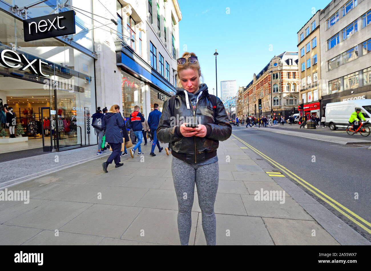 Londres, Angleterre, Royaume-Uni. Jeune femme sur son téléphone mobile dans Oxford Street Banque D'Images