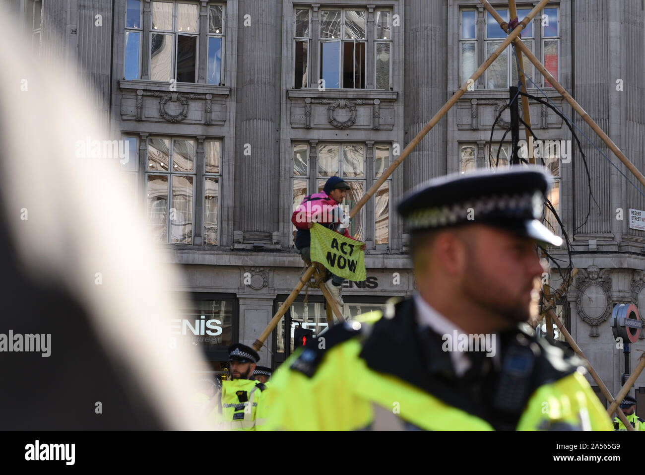 Londres, Royaume-Uni. 18 Oct, 2019. Un militant du changement climatique est titulaire d'un panneau "agir maintenant" comme il est assis dans une structure de fortune dans la région de Oxford Circus. Crédit : Kevin Shalvey/Alamy Live News Banque D'Images