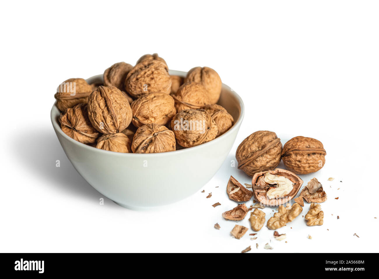 Bol blanc plein de noix de noyer ouvert sur un fond blanc Banque D'Images