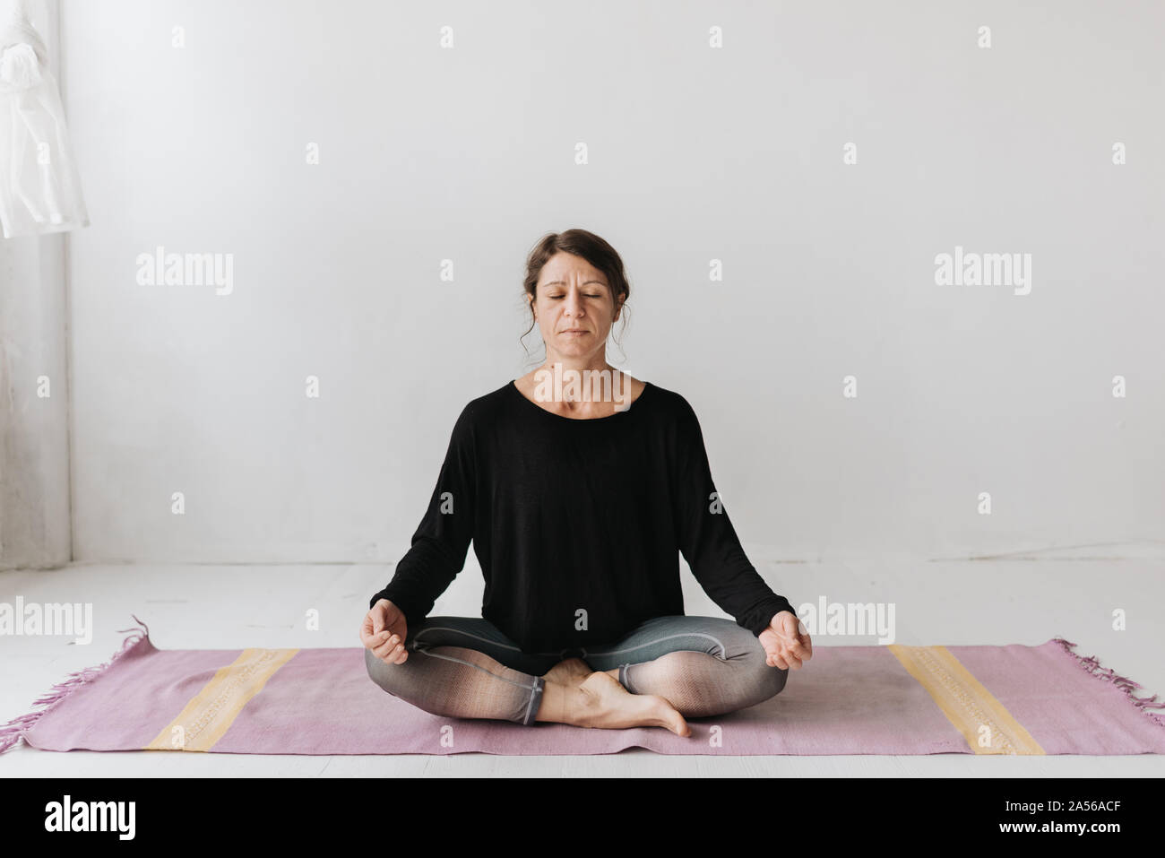 Woman sitting in lotus pose dans le studio de yoga Banque D'Images