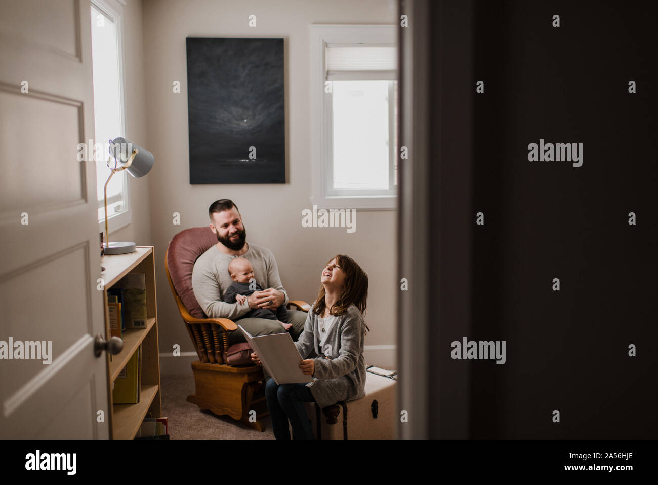 Jeune homme avec son bébé sur les genoux, rire avec sa fille dans la salle de séjour Banque D'Images