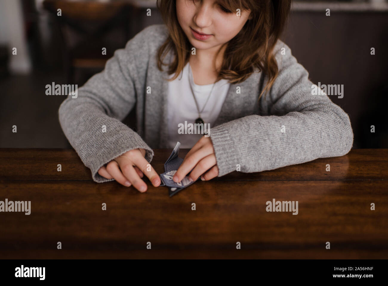 Girl at table folding paper, faisant de l'origami, la tête et épaules Banque D'Images