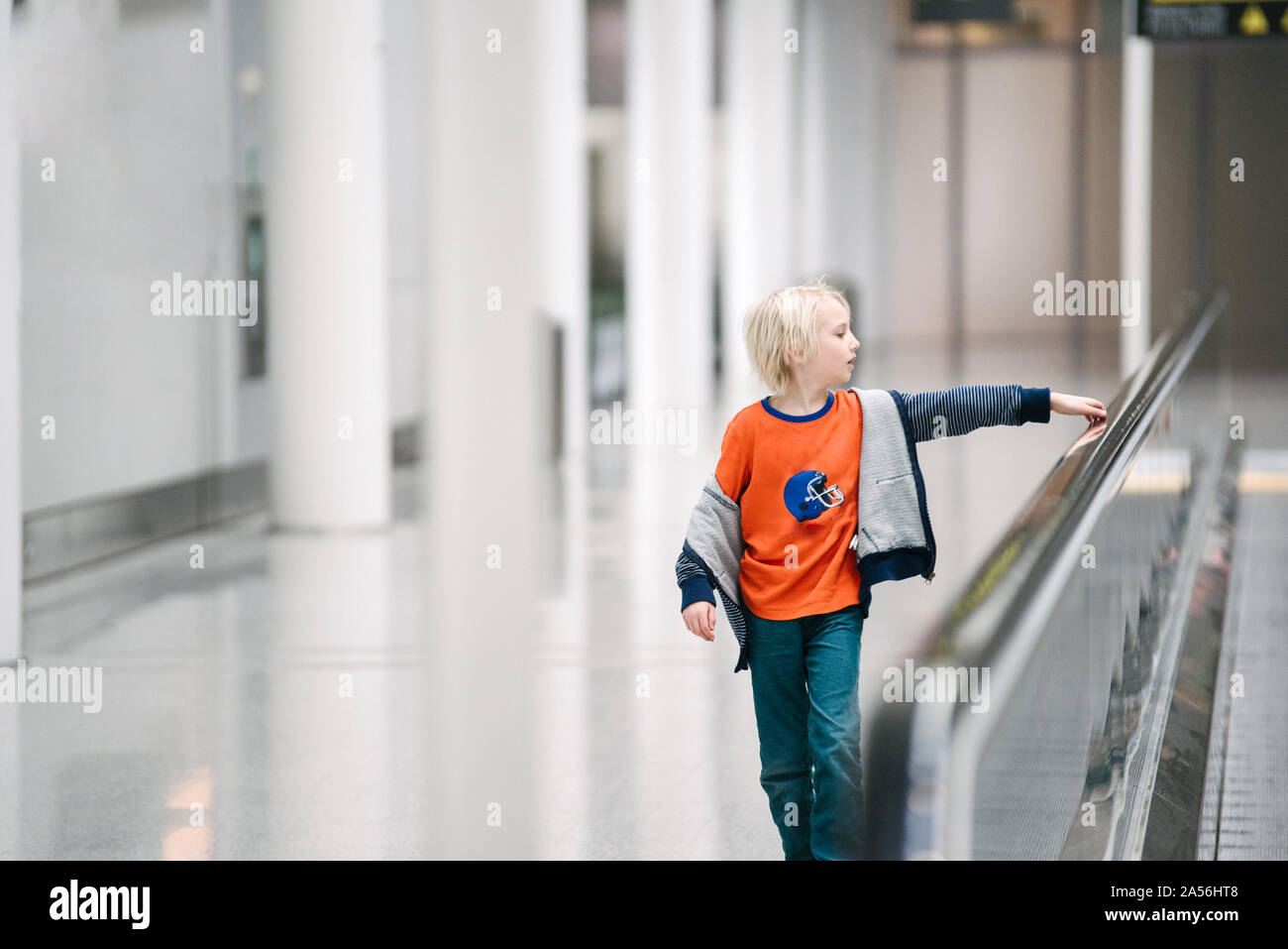 Garçon avec la main sur la main courante de tapis roulant à l'aéroport, selective focus Banque D'Images