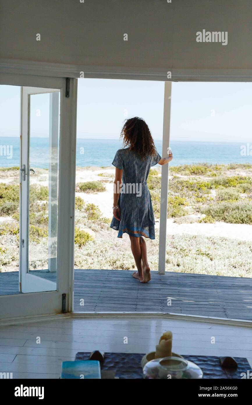 Woman enjoying view de mer sur portique de beach house Banque D'Images