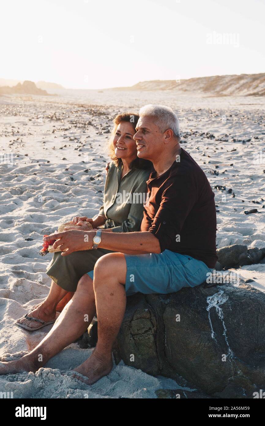 Senior couple enjoying sun on sandy beach Banque D'Images
