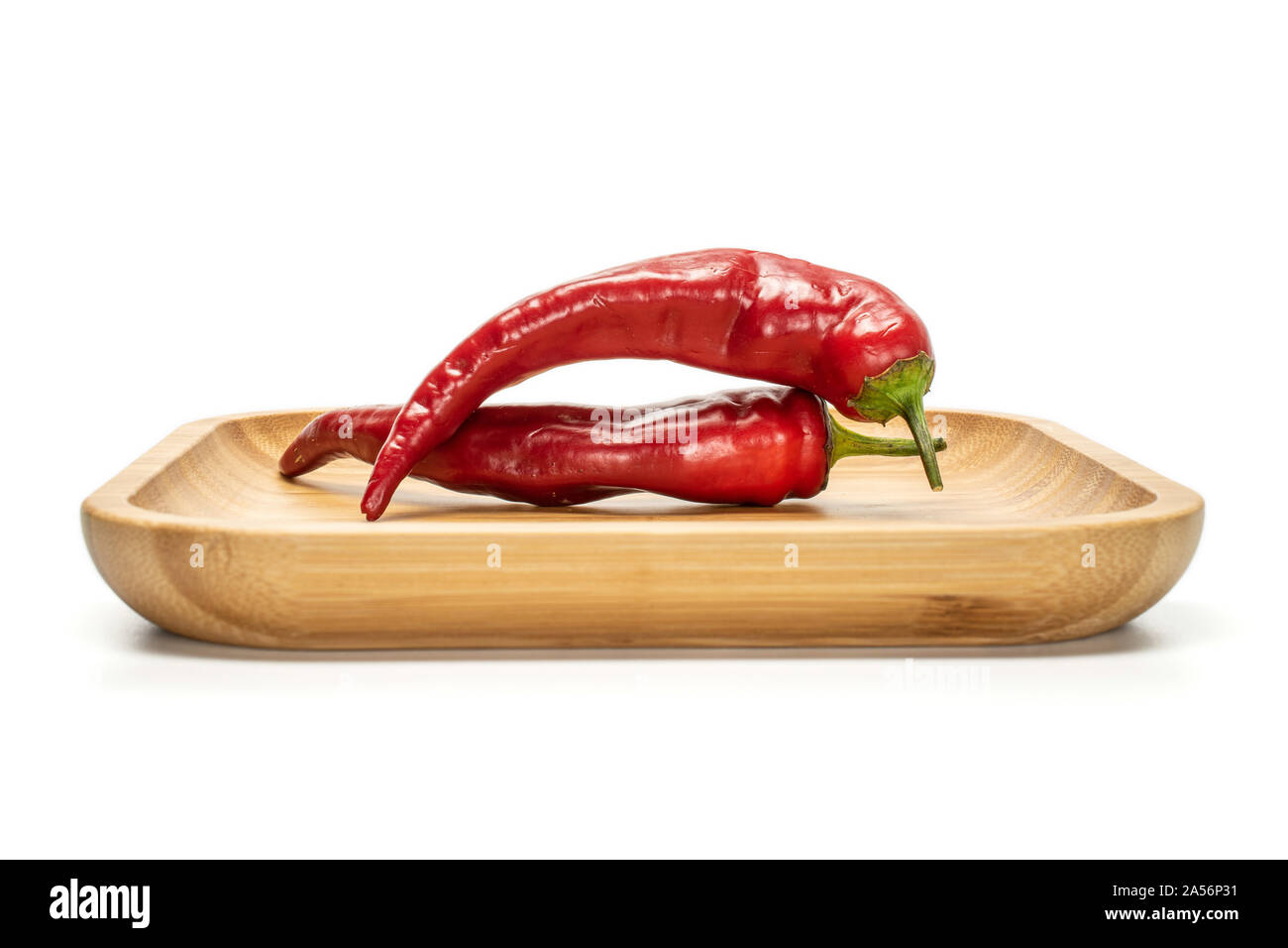 Groupe de deux entiers et frais, le piment sur plaque carrée en bois isolé sur fond blanc Banque D'Images