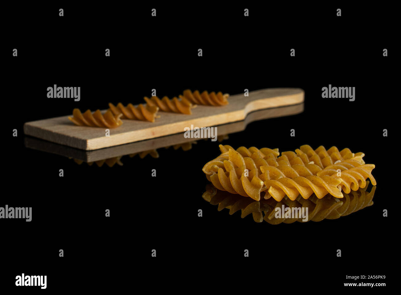 Beaucoup d'ensemble complet sur fusilli secs brown petite planche à découper en bois isolé sur verre noir Banque D'Images