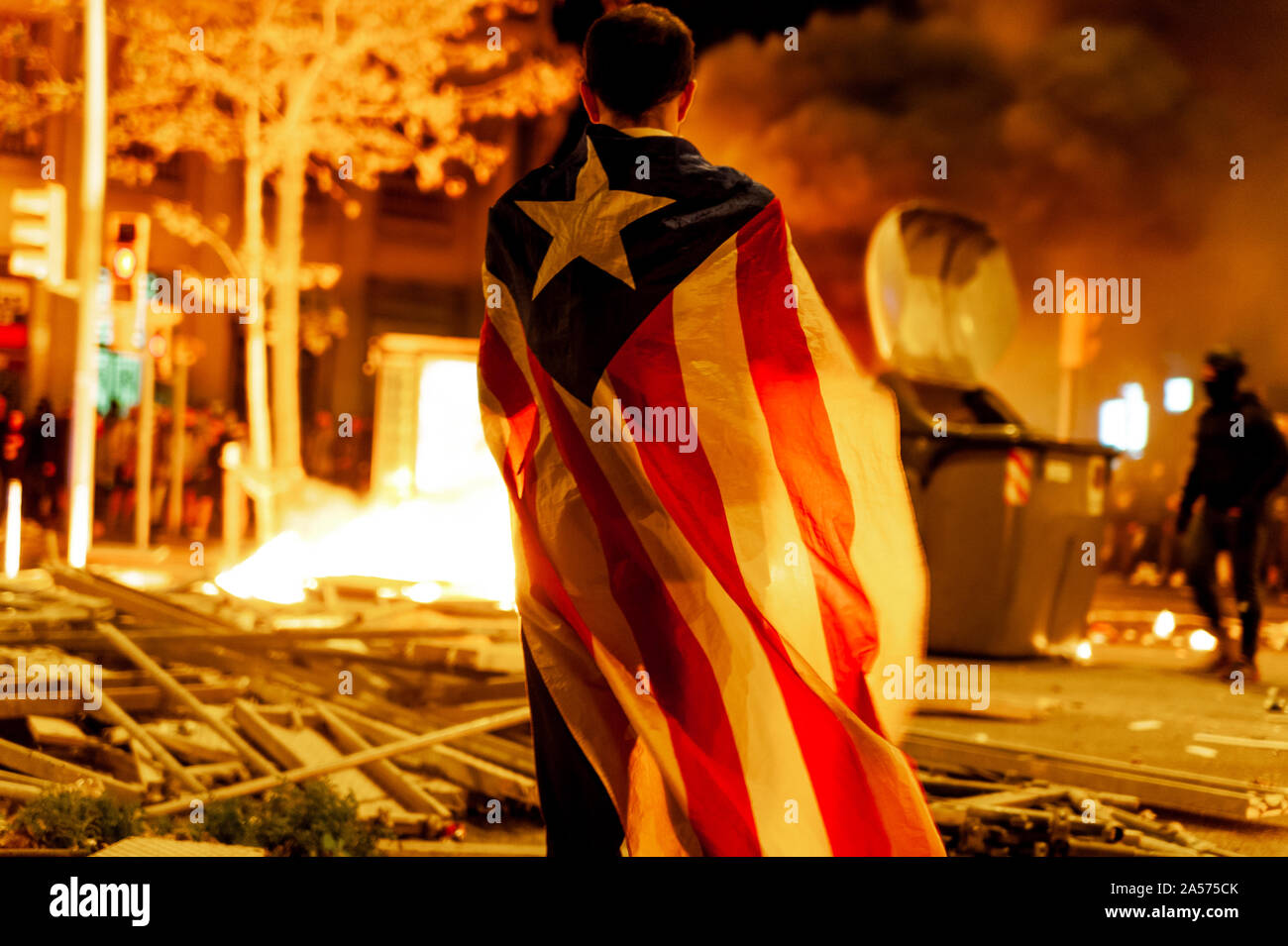 Barcelone, Espagne - 18 octobre 2019 : activiste catalan avec drapeau catalan dans la nuit avec le feu et la destruction en arrière-plan au cours d'affrontements avec la police Banque D'Images