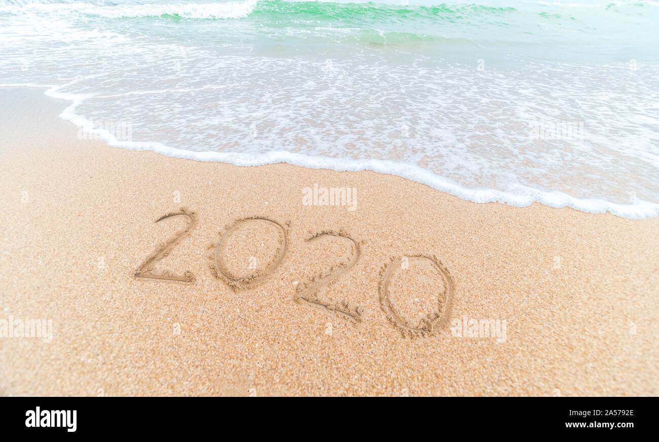 Bonne Année 2020 écrit sur le sable de mer au lever du soleil concept.belle plage de sable et des vagues de l'océan bleu Banque D'Images