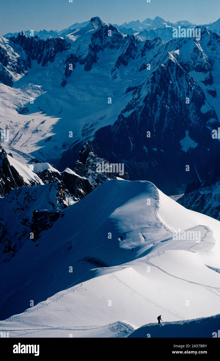 La petite figure de l'alpiniste sur l'Aiguille du Midi avec les montagnes des Alpes au-delà Banque D'Images