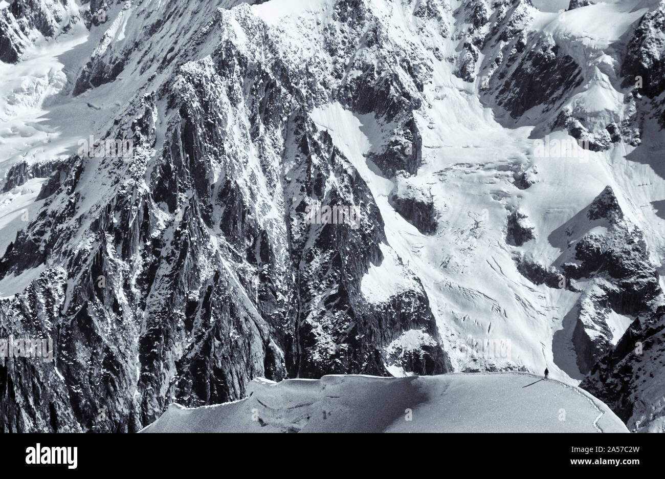La petite figure de l'alpiniste sur l'Aiguille du Midi avec les montagnes des Alpes au-delà Banque D'Images