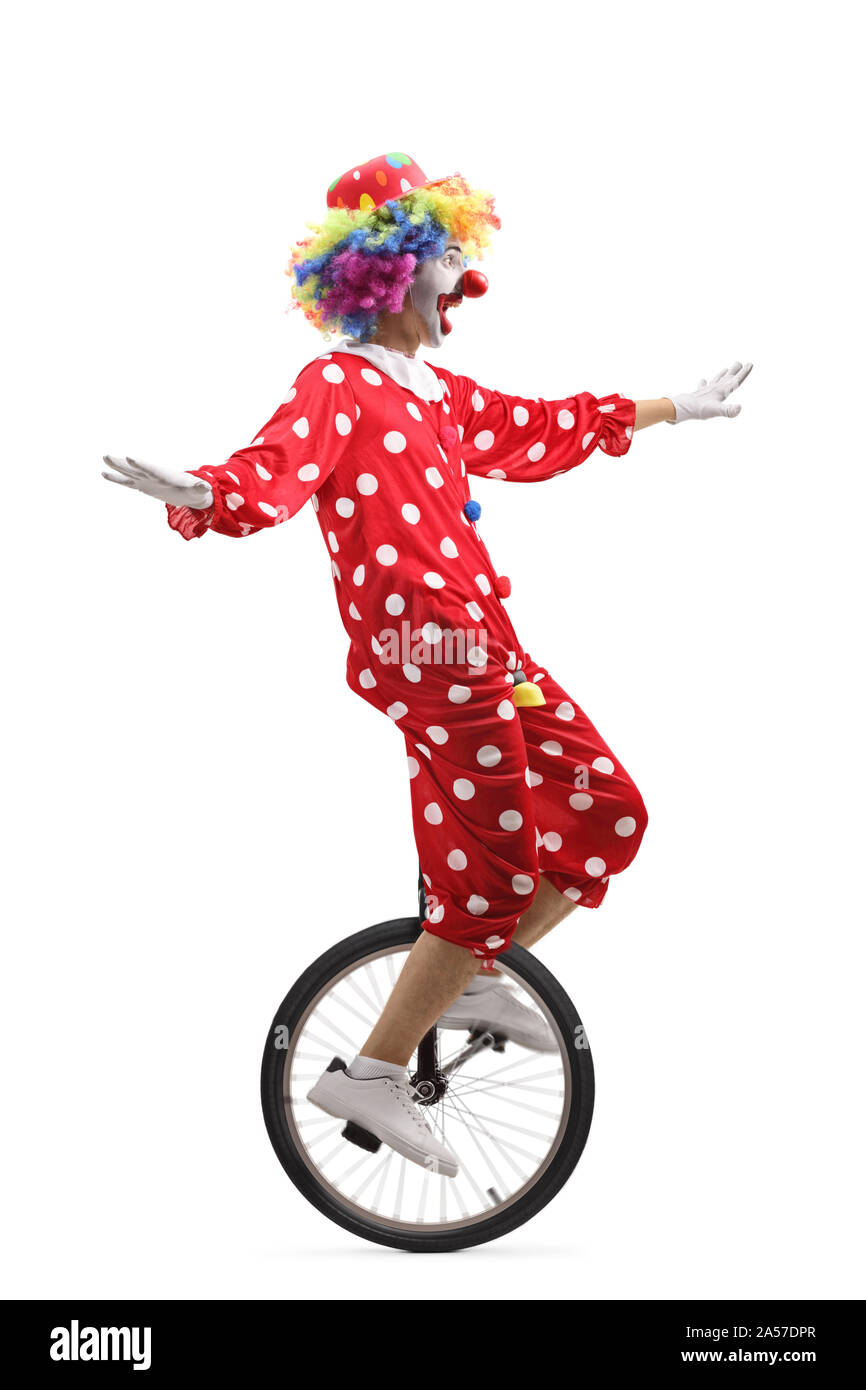 Profil de toute la longueur d'un clown joyeux équitation un monocycle et en faisant une drôle de grimace isolé sur fond blanc Banque D'Images