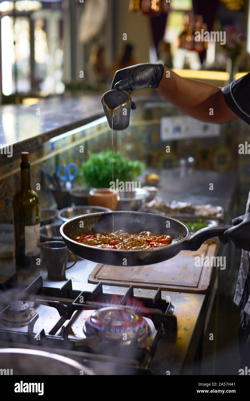 Concept alimentaire. Le chef ajoute les épices dans une casserole, faire frire les tomates et les huîtres. Le processus de cuisson de spaghettis aux fruits de mer. Banque D'Images