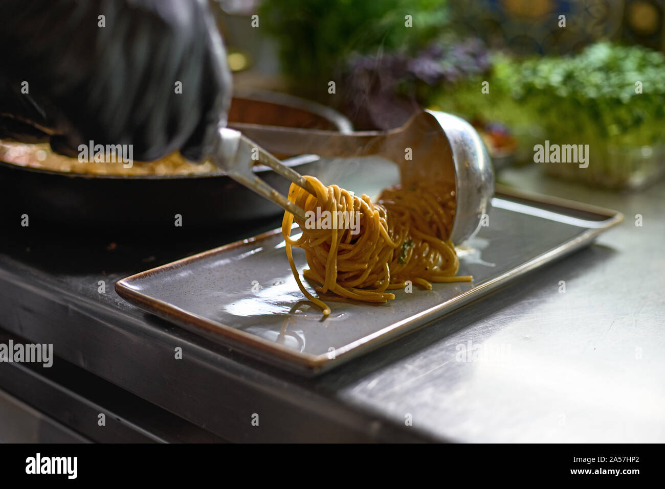 Concept alimentaire. Le chef mélange spaghetti dans une casserole les tomates et les huîtres, le plat dans un restaurant. Le processus de cuisson de spaghettis aux fruits de mer. Banque D'Images