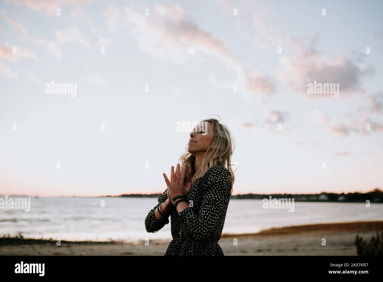 Femme méditant sur la plage au coucher du soleil Banque D'Images