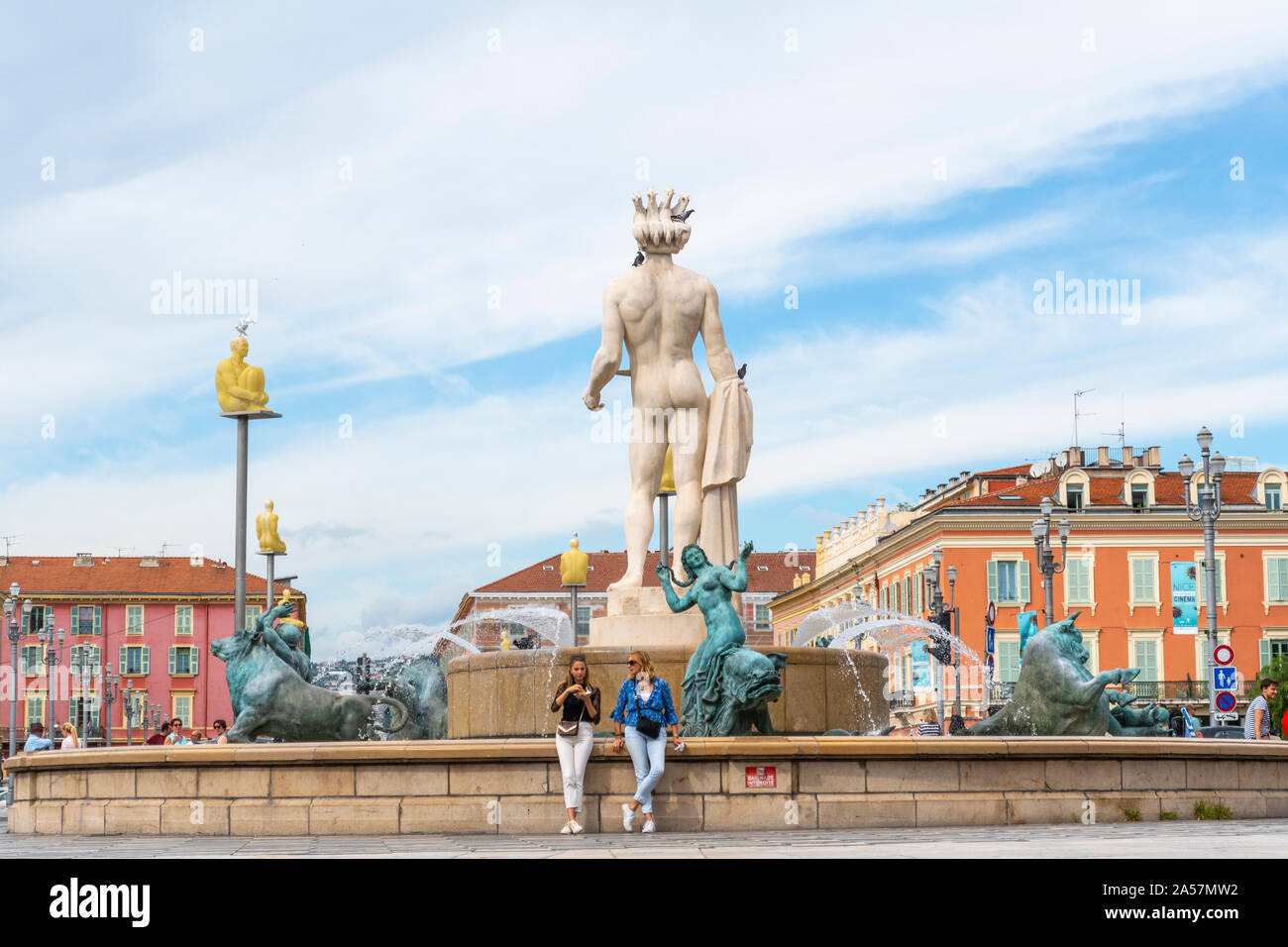 Deux femmes se détendre en face de la statue d'Apollon à la fontaine du soleil dans la Place Masséna, dans la ville de Nice France, sur la côte d'Azur. Banque D'Images