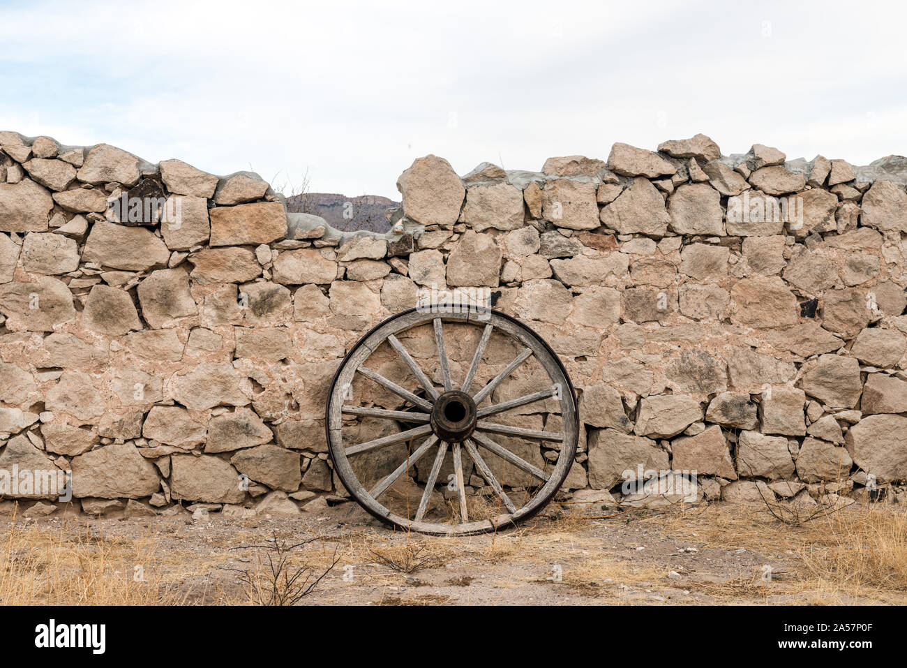 Roue de chariot contre une clôture en pierre à Hueco Tanks State Park, au nord-ouest d'El Paso, Texas Banque D'Images