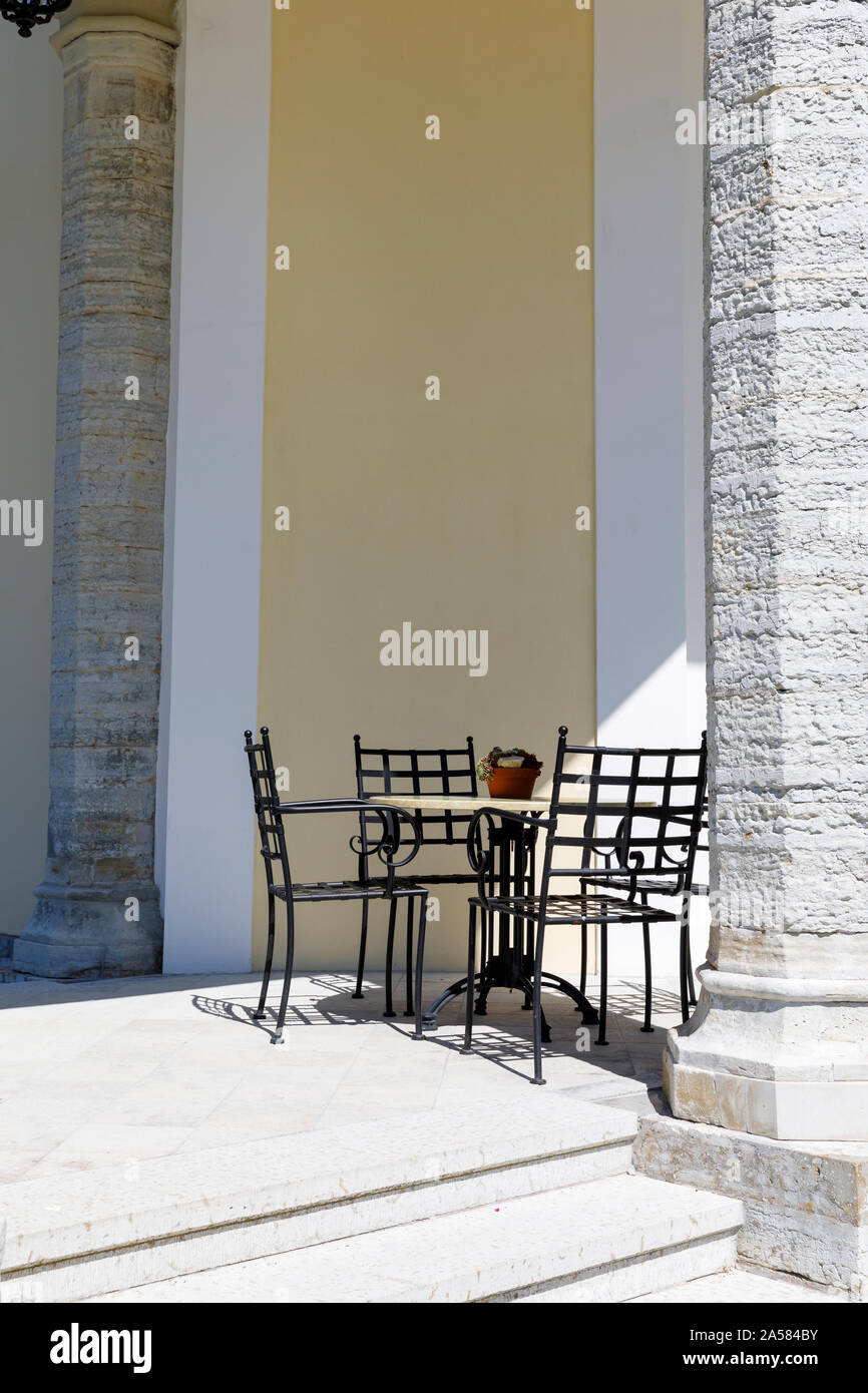 Cafe table et chaises contre la paroi d'un immeuble derrière pilier Banque D'Images