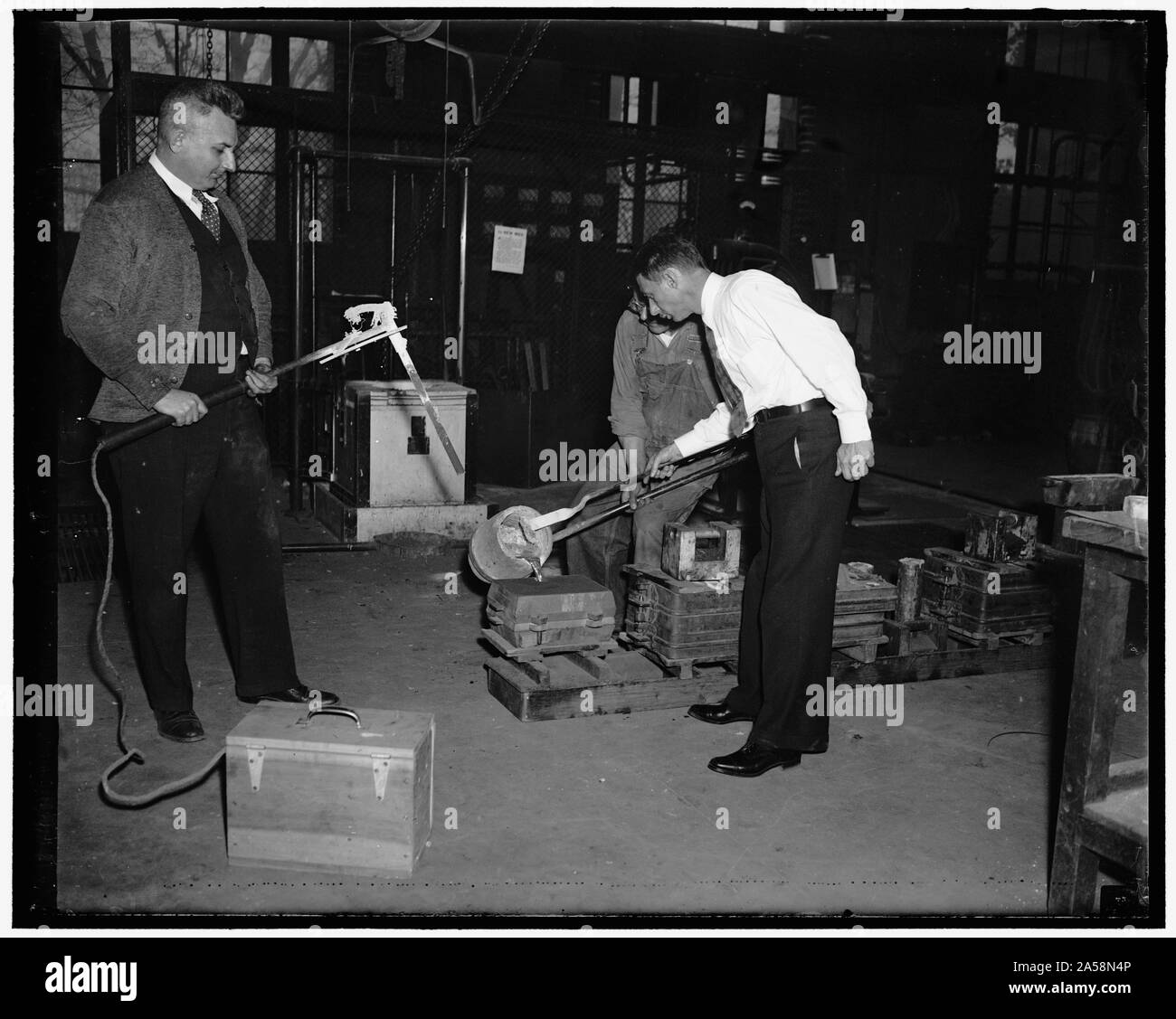 Oncle Sam test alliages de laiton. Washington D.C. pour déterminer la quantité appropriée d'alliages nécessaires aux résultats souhaités dans la fabrication de pièces coulées et autres utilisations, le U.S. Bureau of Standards mène des tests quotidiens. 600 portions différentes de l'alliage sont utilisés à l'heure actuelle. Les tests sont réalisés avec des barres en laiton qui sont fondus dans un four à induction à haute fréquence et les températures sont enregistrées avant et durant la coulée dans les moules. Sur la photo, de gauche à droite : H.V. Gardner, Lemuel D. Jones, et C.N. Saeger, chef de la fonderie expérimentale au Bureau Banque D'Images