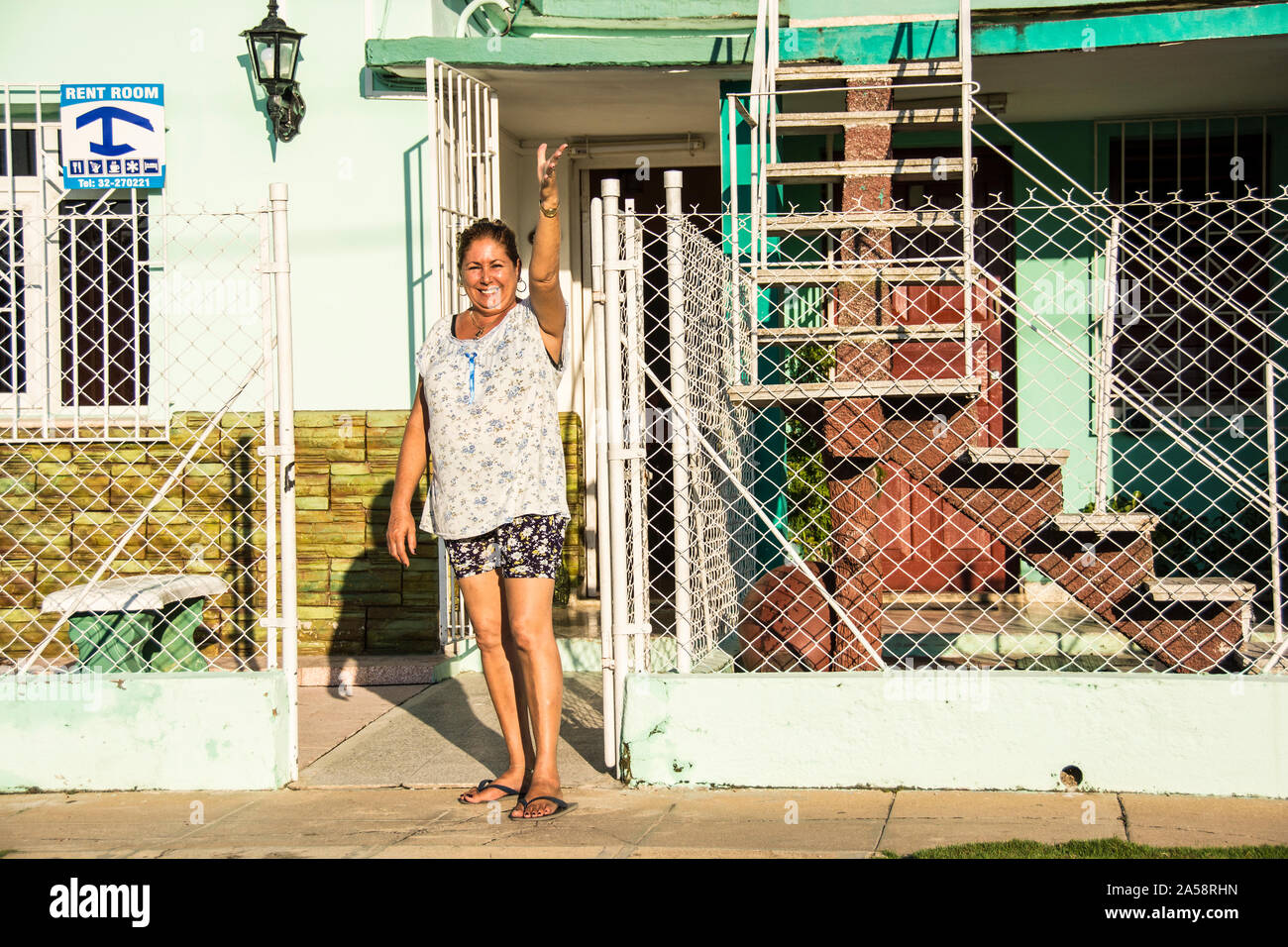 Une femme devant sa maison. Signe derrière elle annonçant que les chambres sont à louer; Camaguey, Cuba Banque D'Images