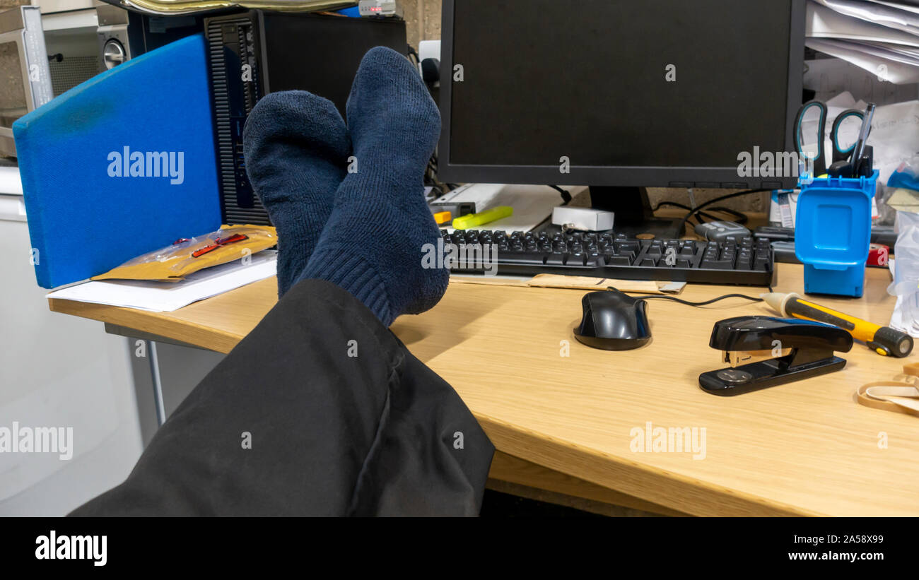 Ingénieur avec ses chaussures et ses pieds sur son bureau à son poste de travail Banque D'Images