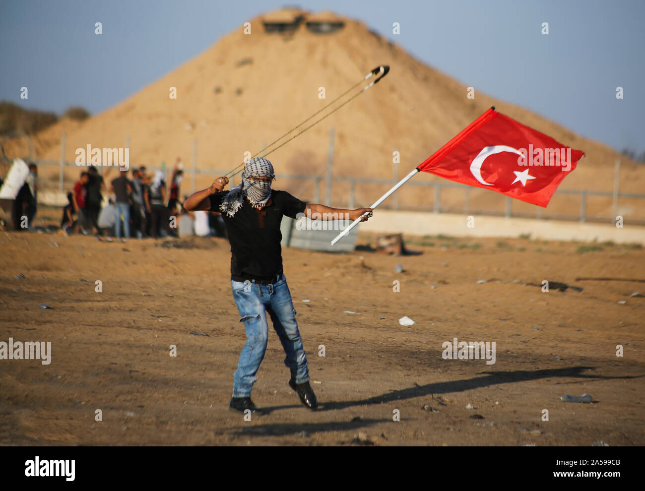 Gaza, la Palestine. 18 Oct, 2019. Un manifestant palestinien avec un drapeau turc utilise une fronde pour lancer des pierres au cours d'une manifestation anti-Israël, appelant à mettre fin à des années de siège sur la frontière Israel-Gaza au sud de Gaza. Credit : SOPA/Alamy Images Limited Live News Banque D'Images